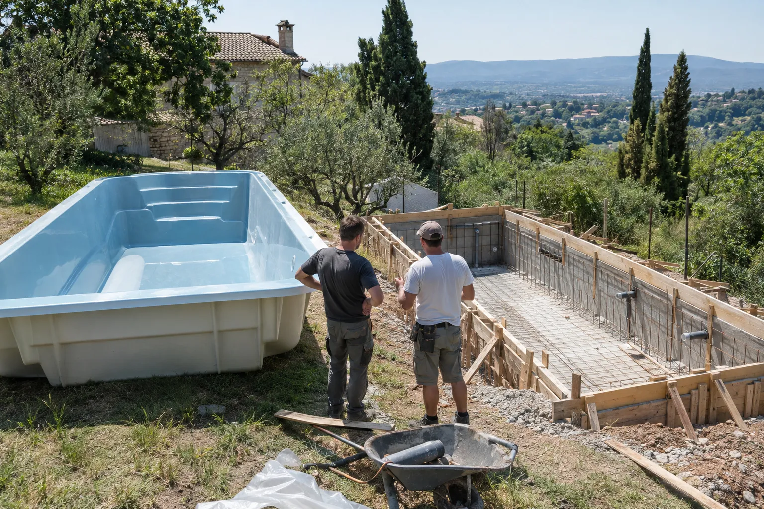 Une coque de piscine posée sur l’herbe à côté d’un bassin béton en coffrage, deux artisans qui en discutent
